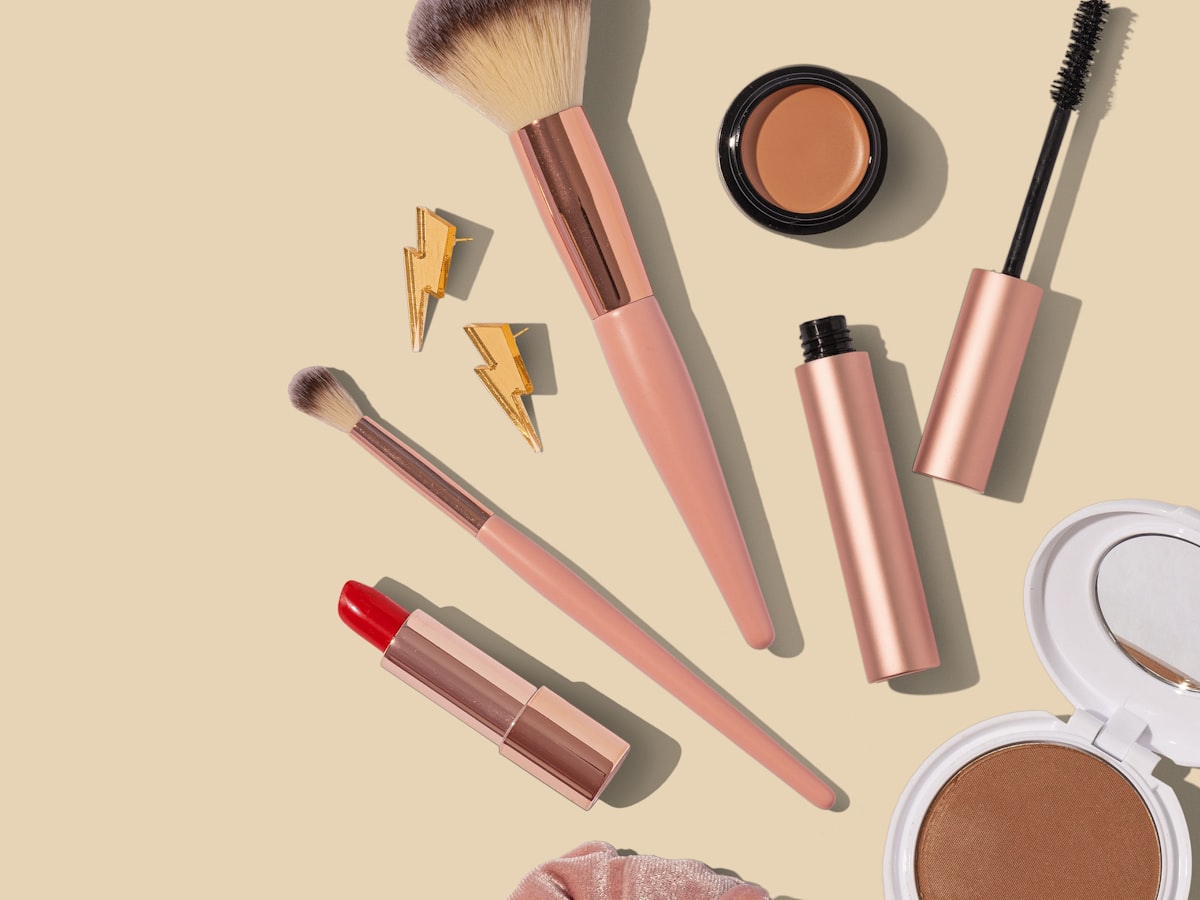 Brushes, compacts and colour products arranged on a cream surface