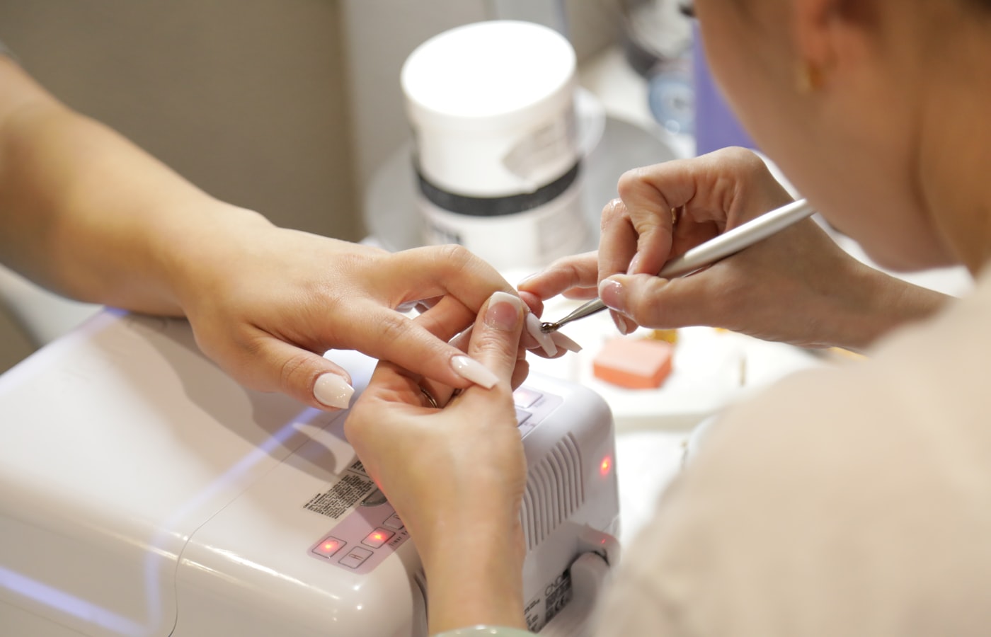 A technician working on a client's manicure at a studio desk